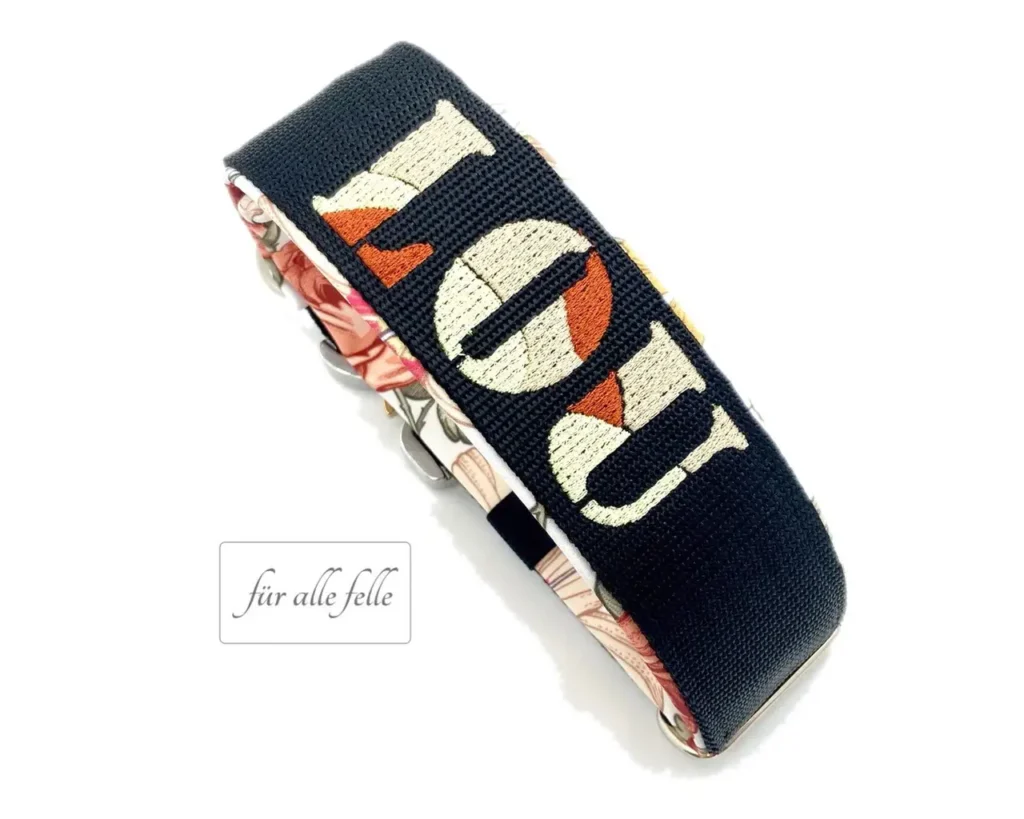 Breites Hundehalsband in schwarz mit dem Namen 'LOU' in cremeweiß und braun bestickt, akzentuiert mit einem eleganten floralen Innenfutter, handgefertigt von 'Für alle Felle'
