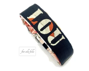 Breites Hundehalsband in schwarz mit dem Namen 'LOU' in cremeweiß und braun bestickt, akzentuiert mit einem eleganten floralen Innenfutter, handgefertigt von 'Für alle Felle'